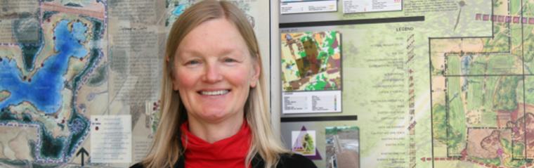 Karen Landman smiling in front of large landscape sketch