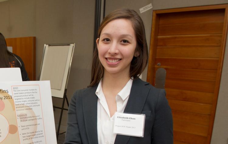 Lizzie in suit jacket with name tag in front of presentation board