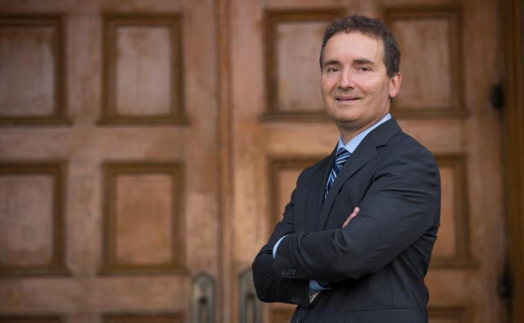 Rene Van Acker in front of wooden doors with arms crossed