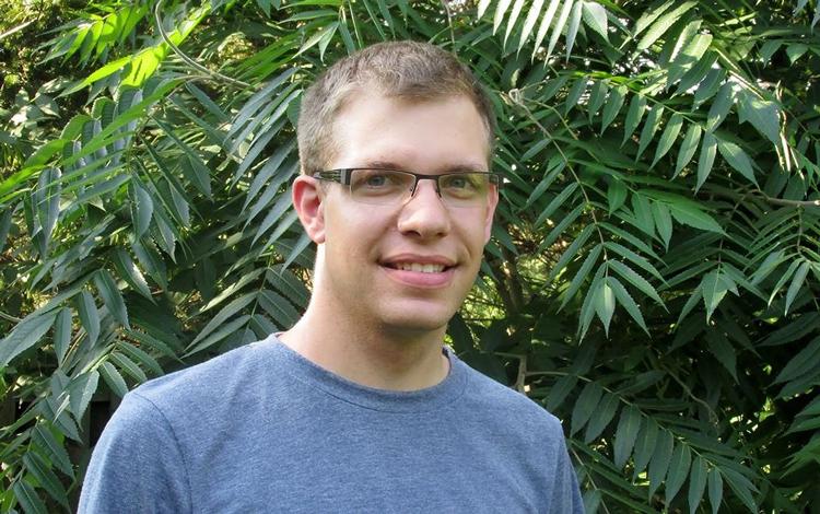 Scott in blue shirt in front of leafy plant