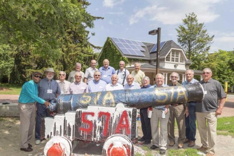 The OAC class of 57 stands around the cannon