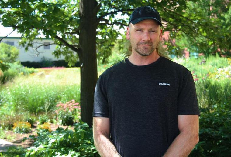 Thomas Graham in black t-shirt and hat, standing outside