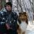 Cameron kneels with his dog Murphy in a snowy woods.