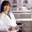 A woman in a white lab coat holding a notebook in a lab.