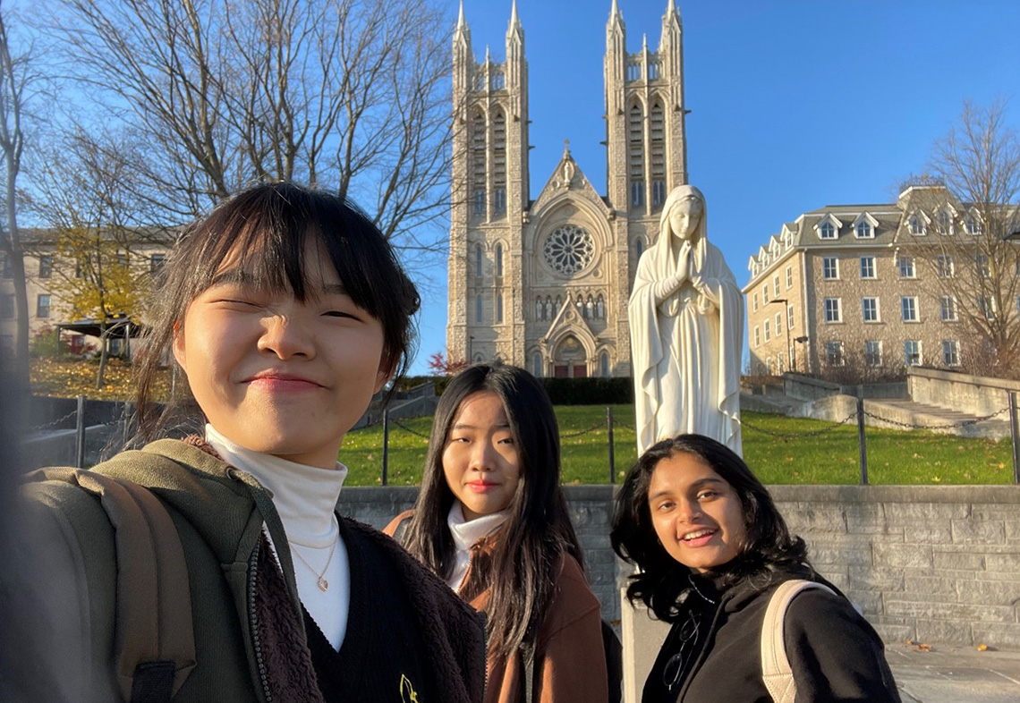 Three students posing in front of an old church. 