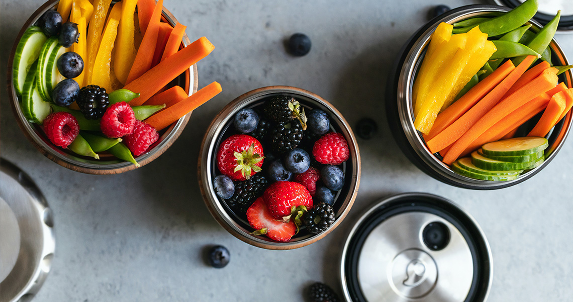 Three containers of bright fruit and vegetables, that includes peppers, cucumbers, carrots and berries.