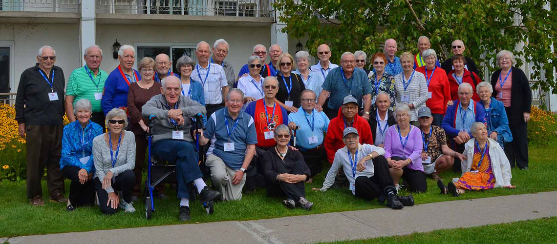 Class of 1962 and their spouses stand together in a large group
