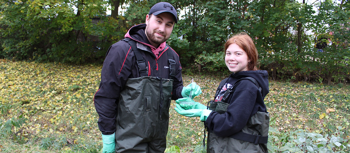 Two students in hip waders taking field samples.
