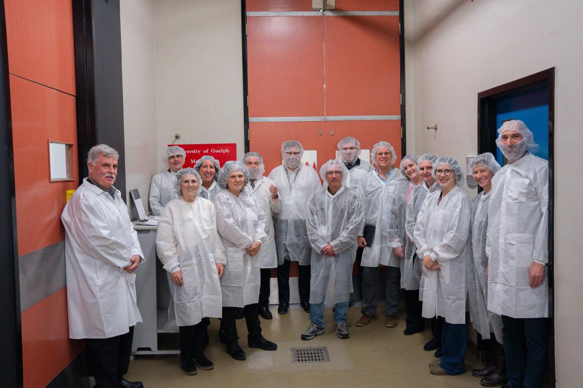 attendees pose for a picture in the meat lab facility. everyone is wearing lab coats