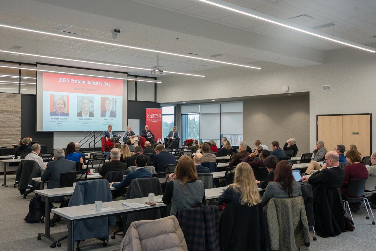 a full room of people at the event with the panelists on stage. 