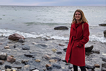 Danielle standing on a shore with a body of water in the background.