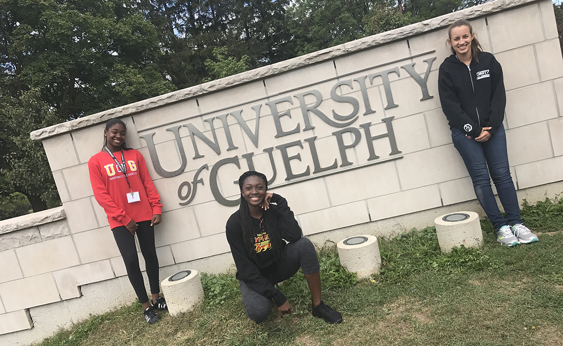 Three students pose in front of a University of Guelph sign.