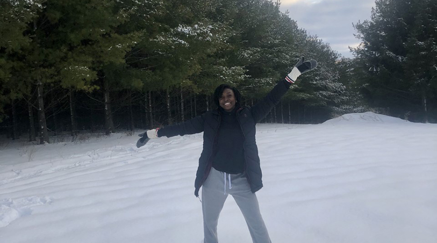 E'layna standing in the snow in front of a forest.