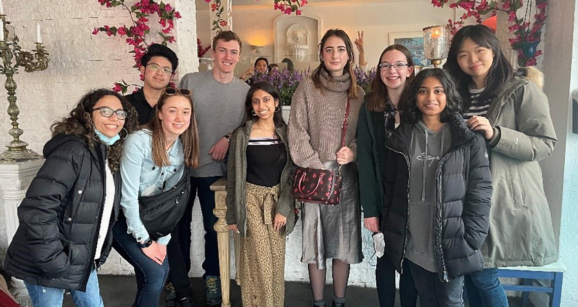 A diverse group of nine students standing together and smiling. 