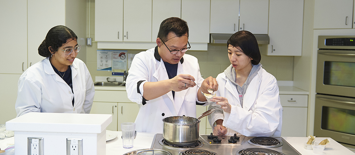 Students in a kitchen making a food product.