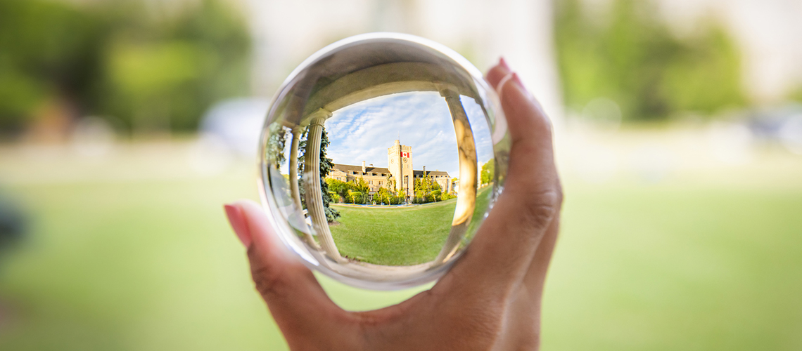 A hand holding a crystal ball that focuses on Johnston Hall.