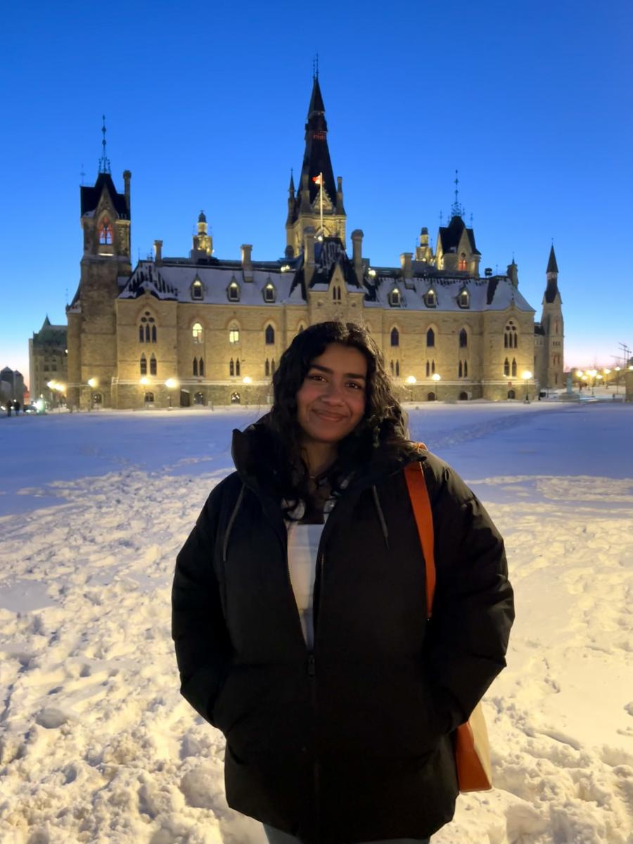 Vedika Stands In Front of the Canadian Parliament building smiling. 