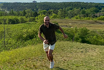 Ibrahim smiling with a field of greenery behind him.