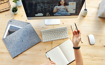 A person doing work at a desk while watching a video.