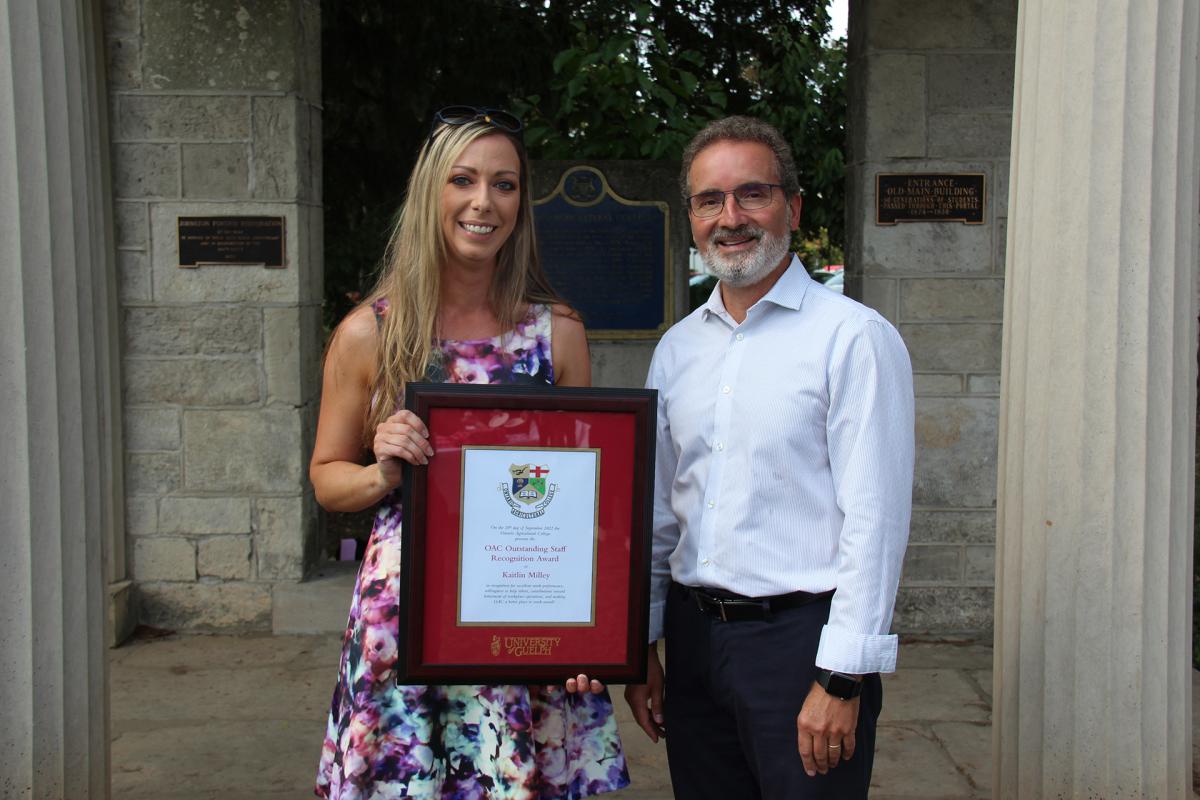 Kaitlin holding a frame standing next to the OAC Dean.