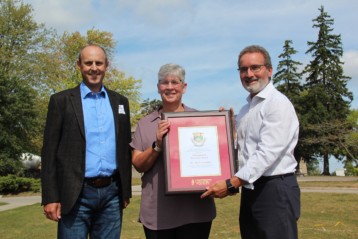 A man on the left in business casual clothing, a woman with short hair holding an award in the center, and a man in a white button up and a beard on the right.