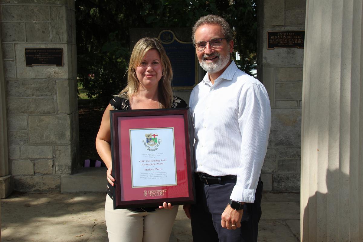 Marlene holding a frame standing next to the OAC Dean.