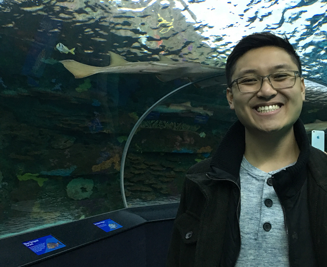 Nick smiling at an aquarium with a shark in the background.