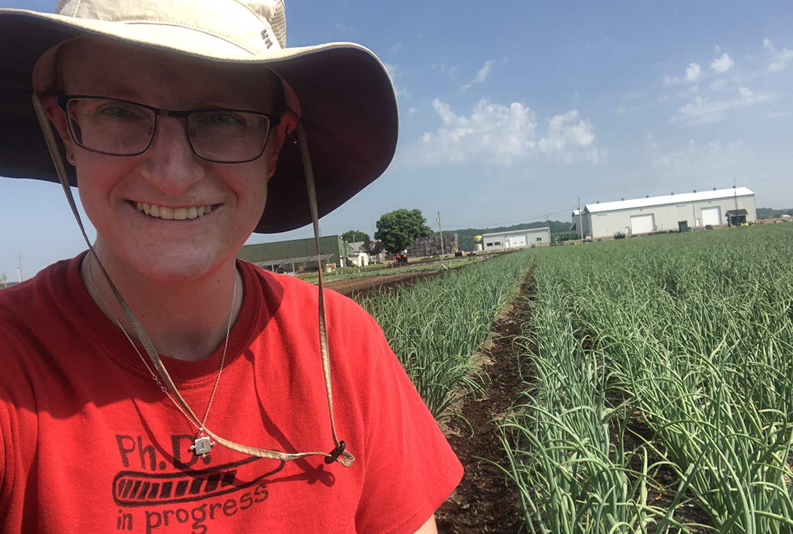 Sara working in a field of onions on a sunny day.