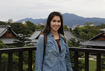 Sonia smiling with houses and greenery in the background.