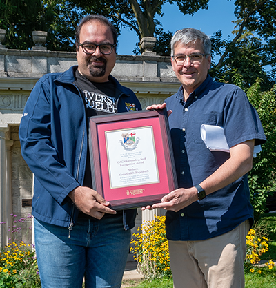 dr. mohsen and john cranfield holding the plaque award