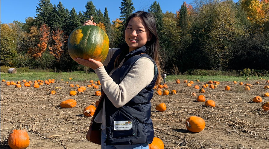 Victoria holding a pumpkin in a pumpkin field.