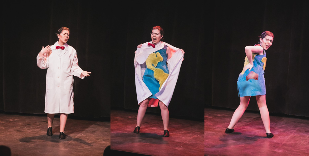 Big Mike in their climate change drag performance showing a transition between a lab coat to a dress with the world map on it.