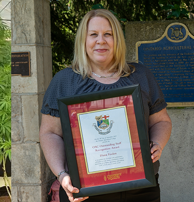 diana foolen holding her award in front of the portico