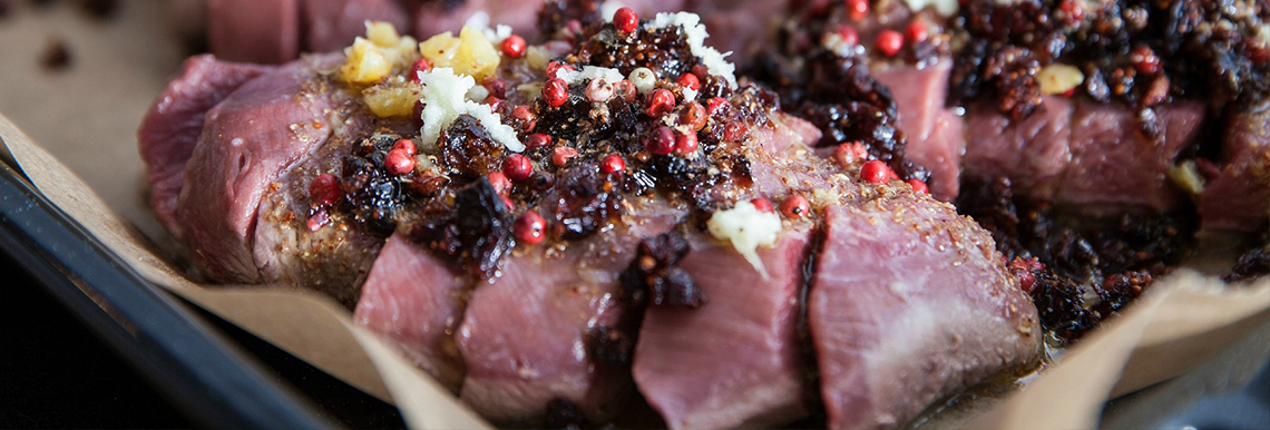 Duck breast marinating on a baking sheet.