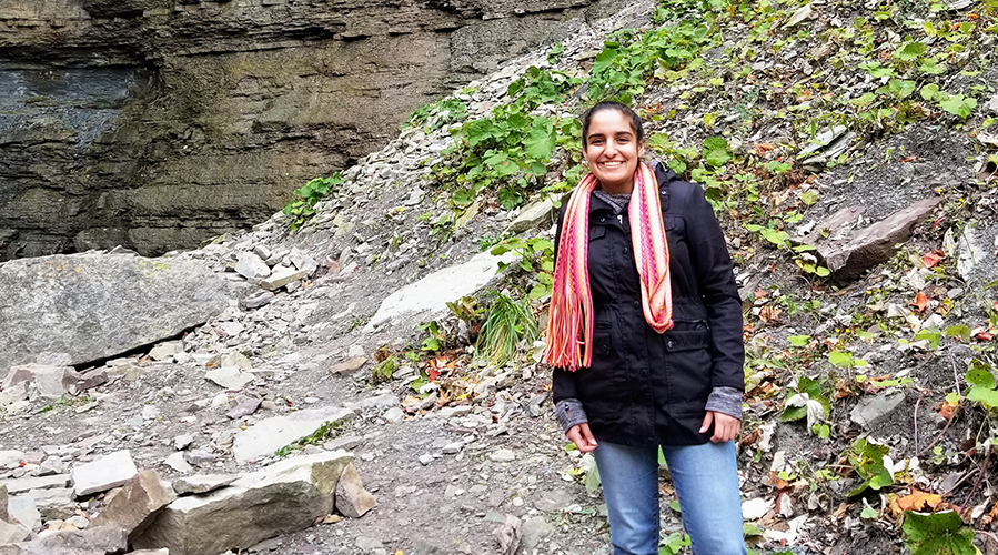Gurleen smiles while standing near a rock formation.