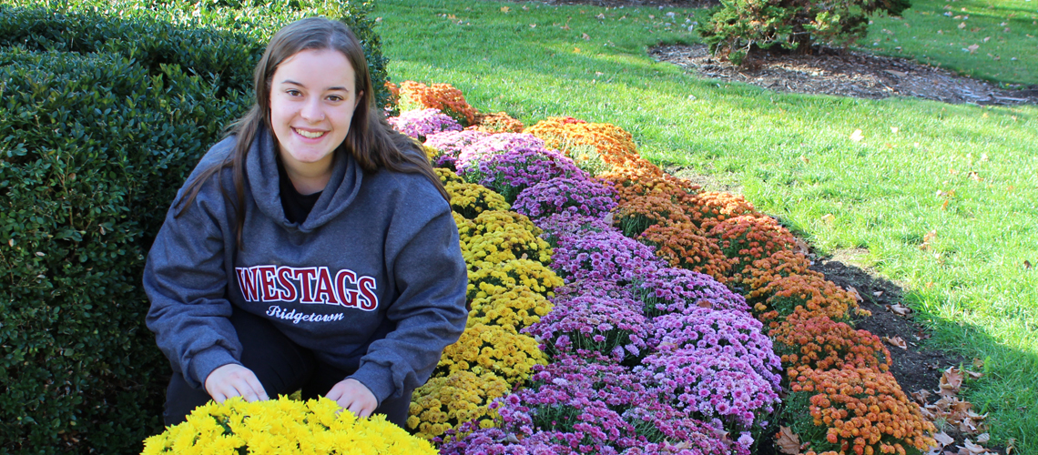 Female student sits in colourful garden