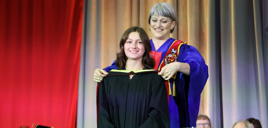 julianna at convocation, with her robe being put over her head