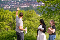 Three students with clip boards overlooking a subdivision near a wooded area. 