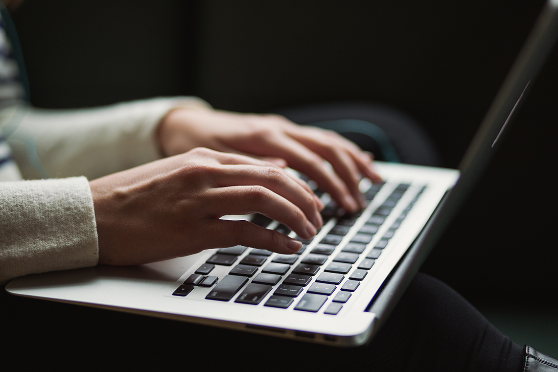 A pair of hands typing on a laptop.