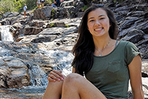 Vanessa sitting in front of a small waterfall at a conservation area.