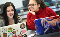 Students laughing while on their computers.