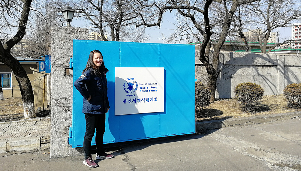 Carol stands in front of the World Food Program sign.