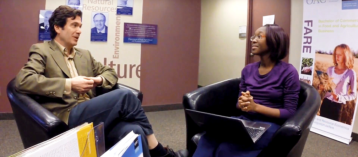 A professor and student sit discussing research.
