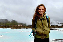 Jamie stands with a bright blue lake and mountains behind her.
