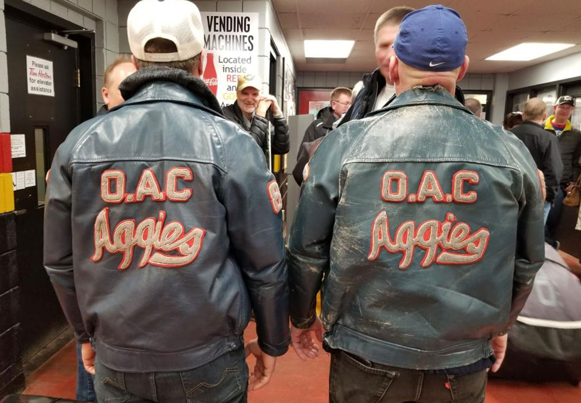 Two men with leather jackets on that say OAC Aggies