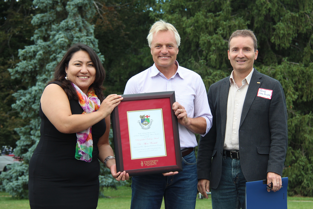 Rocio Morales Rayas, Alfons Weersink and Rene Van Acker pose outside with framed certificate