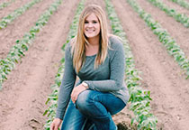 Amy kneels in a corn field.