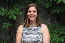 Cara Cargo-Froom stands outside in front of an ivy covered wall.