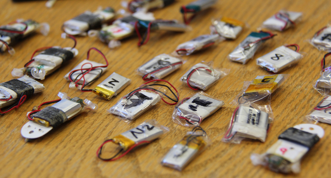 Multiple dataloggers with wires and tape on them sit on a brown wood table