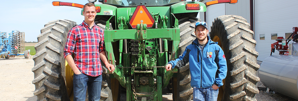 Dylan and friend pose in front of a tractor. 